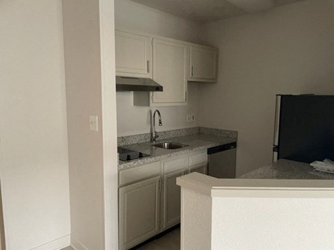 an empty kitchen with white cabinets and a sink
