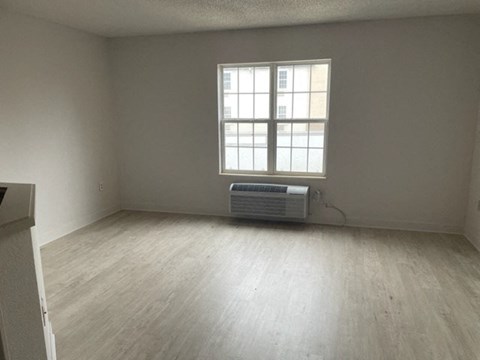 an empty living room with a window and wood floors