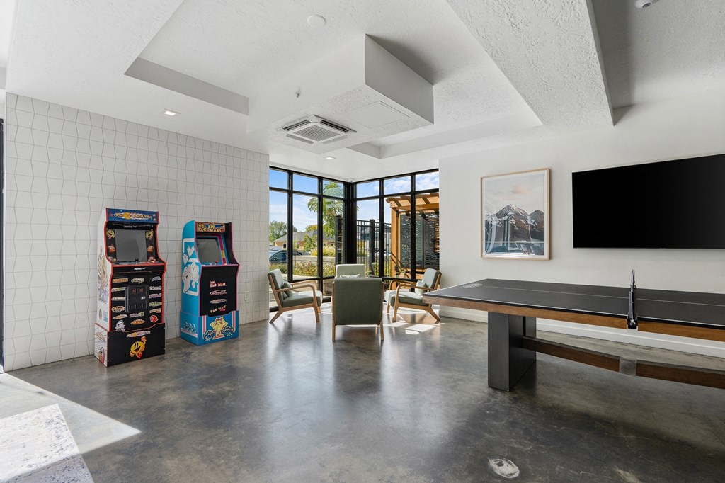 a living room with a pool table and a large window at The Flats at Riverwoods, Provo, Utah