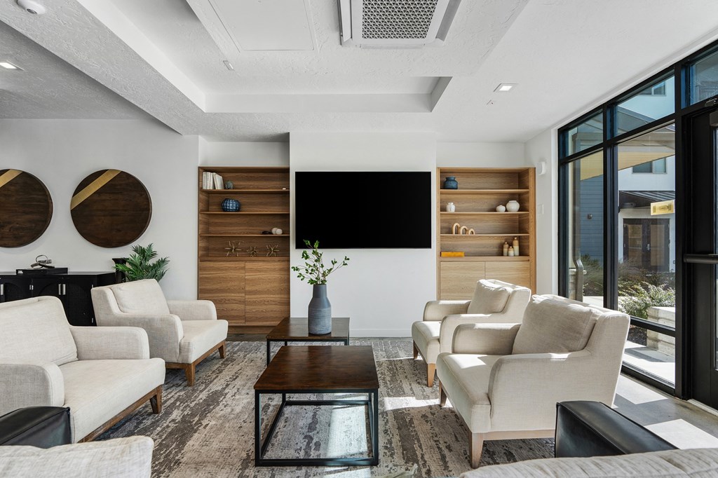 a living room with white furniture and a large window at The Flats at Riverwoods, Provo