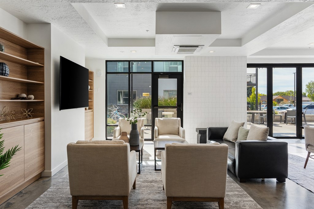 a living room with chairs and a table and a television at The Flats at Riverwoods, Provo