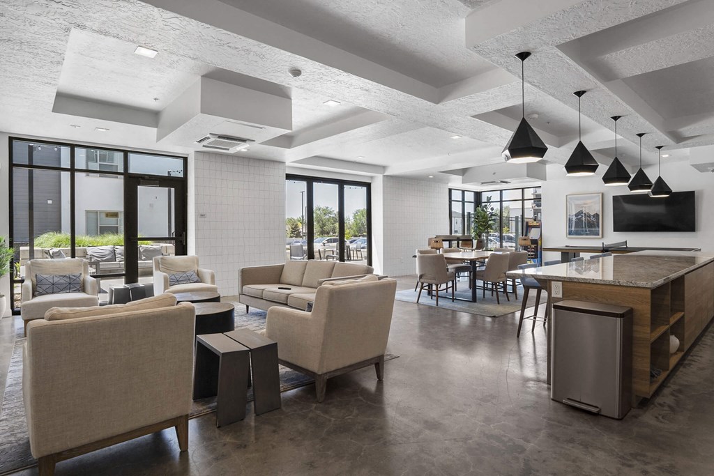 a common room with couches and chairs and a kitchen with a breakfast bar and a television at The Flats at Riverwoods, Provo, Utah