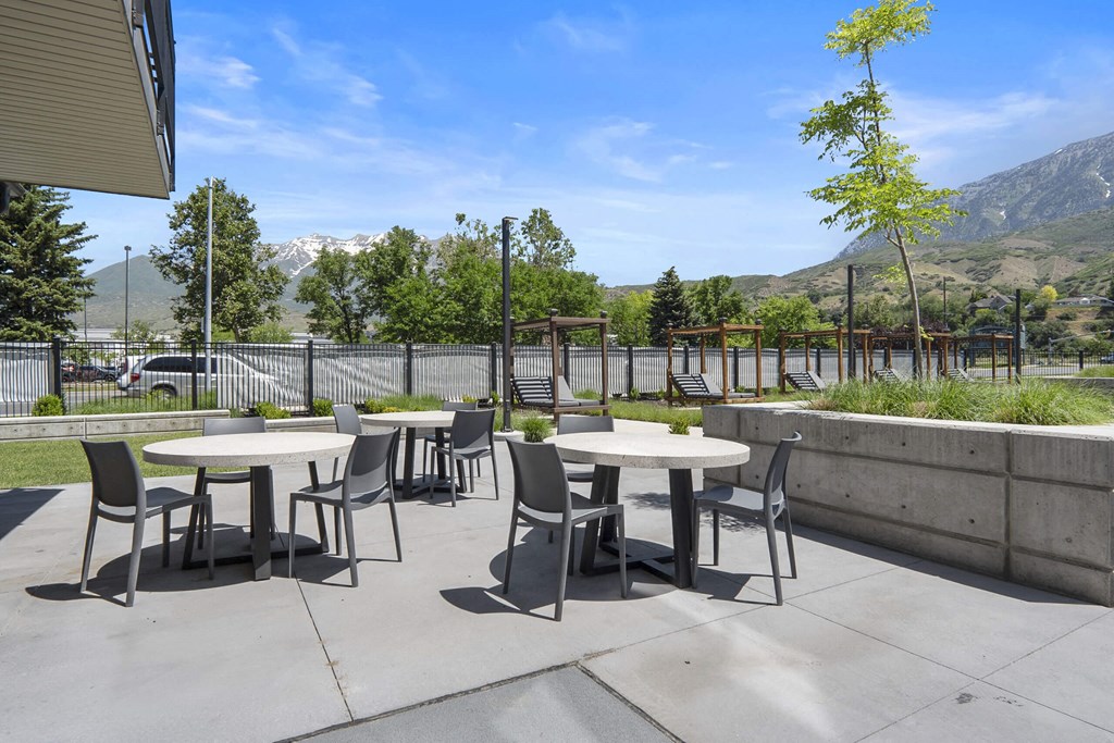an outdoor patio with tables and chairs at The Flats at Riverwoods, Provo
