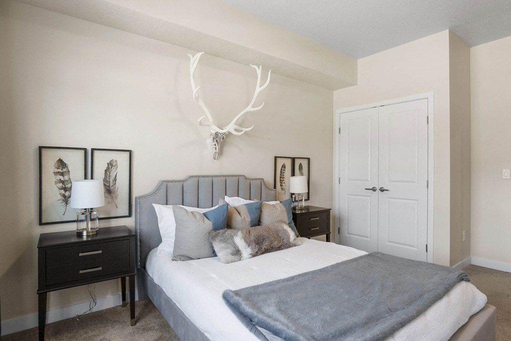 a bedroom with a white bed and antlers on the wall at The Flats at Riverwoods, Provo, Utah