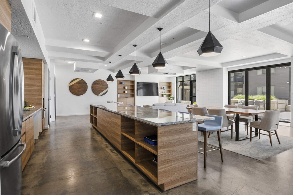 a kitchen with a large center island with a breakfast bar and a dining room in the background at The Flats at Riverwoods, Provo, Utah
