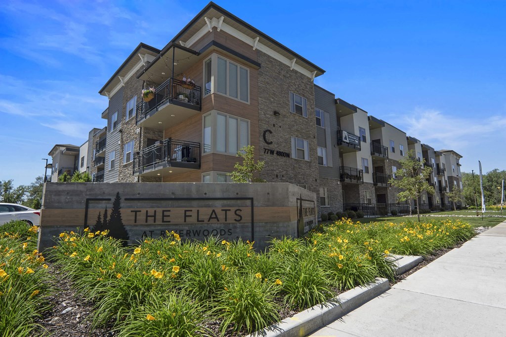 an apartment building with a sign that reads the flats at The Flats at Riverwoods, Provo