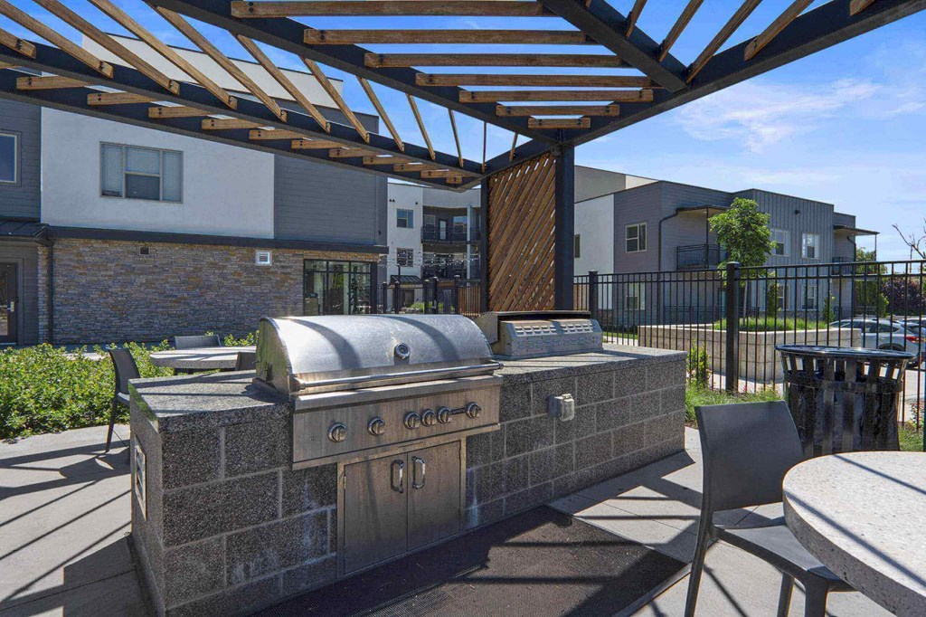 a patio with a grill and tables and chairs at The Flats at Riverwoods, Provo, Utah