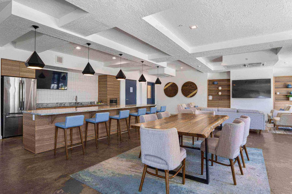 a dining area with a wooden table and chairs and a kitchen with a refrigerator and a microwave at The Flats at Riverwoods, Provo