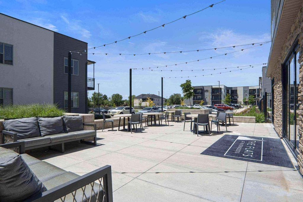 a patio with couches and chairs and string lights in front of a building at The Flats at Riverwoods, Utah