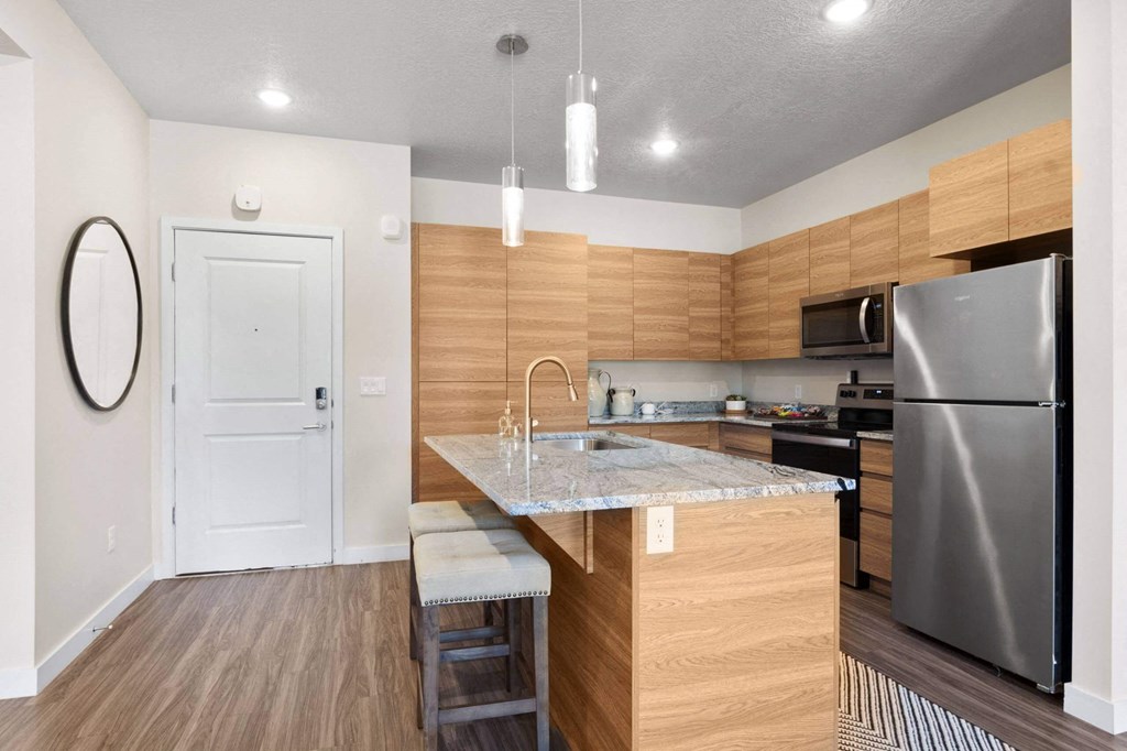 a kitchen with an island and stainless steel appliances at The Flats at Riverwoods, Provo, Utah