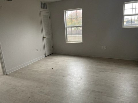 an empty living room with wood floors and a window