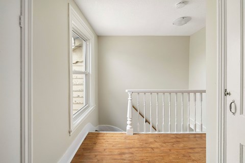 A white interior with a wooden floor and a staircase.