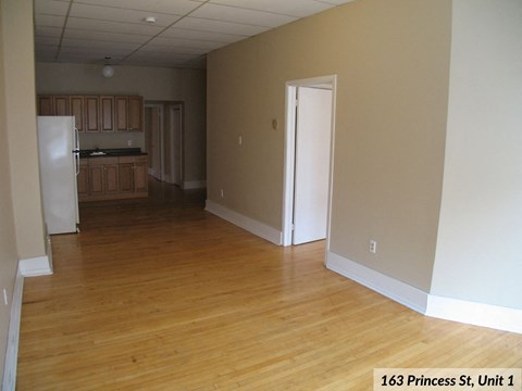 an empty living room and kitchen with wood floors