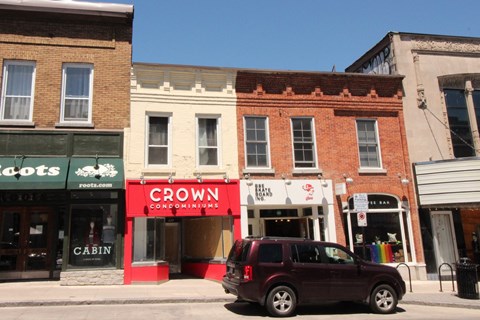 a car parked in front of a row of stores on a city street