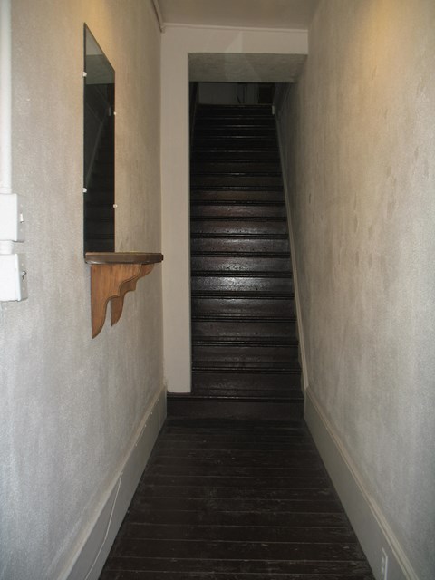 a stairwell with a wooden floor and a window on the side of a wall