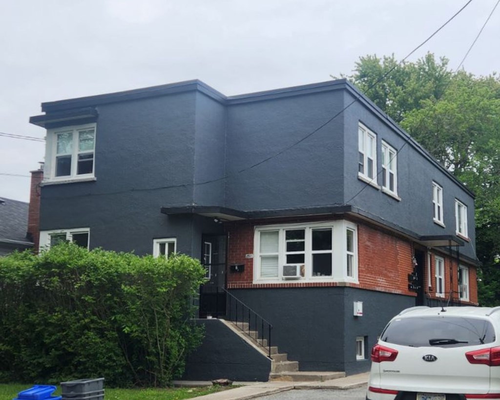 A grey house with a white car parked in front.