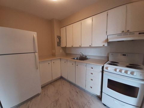 A kitchen with white appliances and cabinets.