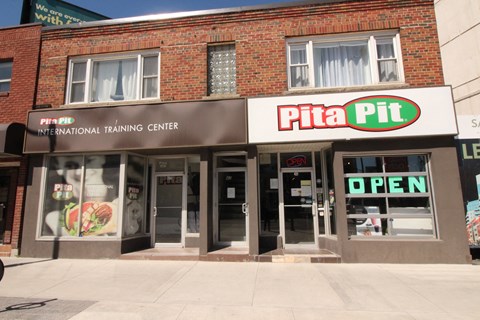 A brick building with a Pita Pit sign on the front.