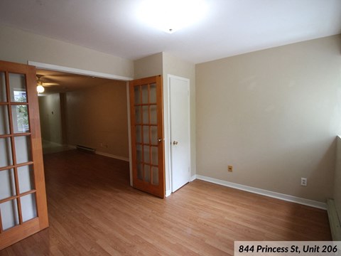 the living room and dining room of a house with wood flooring and a door