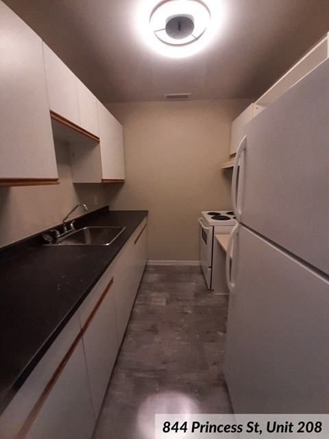 a kitchen with white cabinets and a sink and a refrigerator