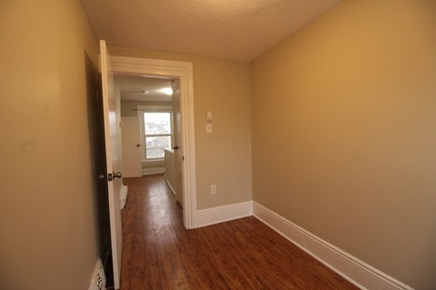 a living room with a hard wood floor and a door to a hallway