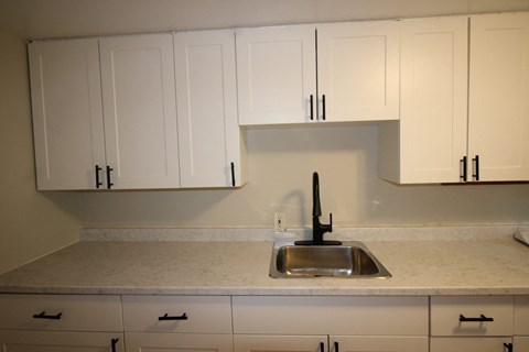 A kitchen with white cabinets and a sink.