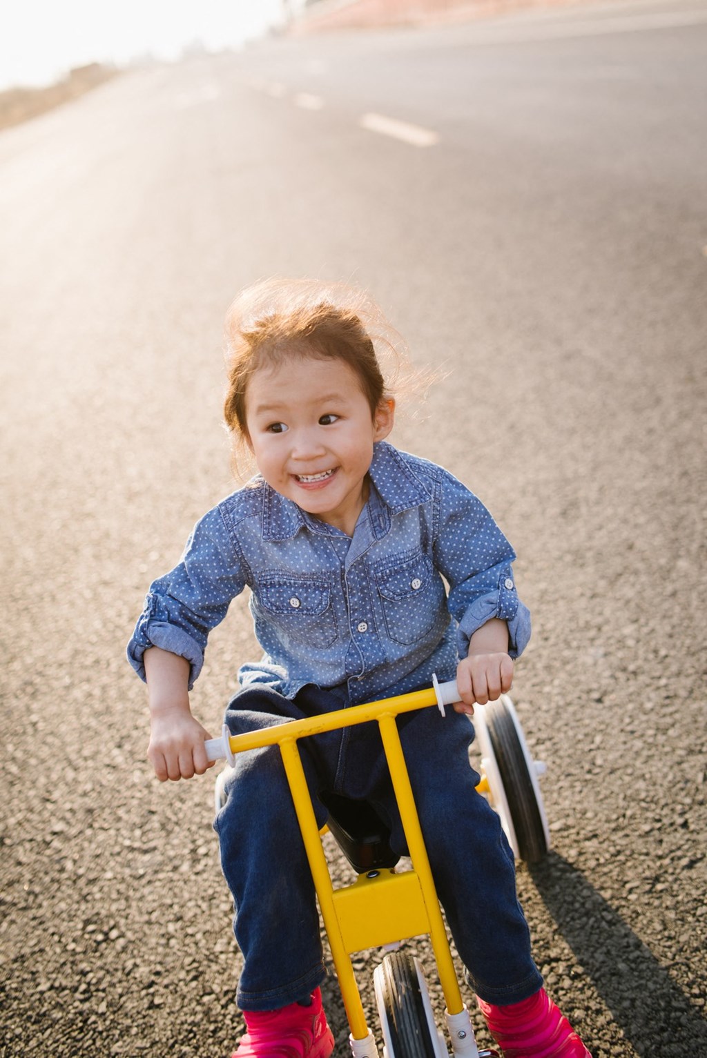a little girl riding a tricycle down the road