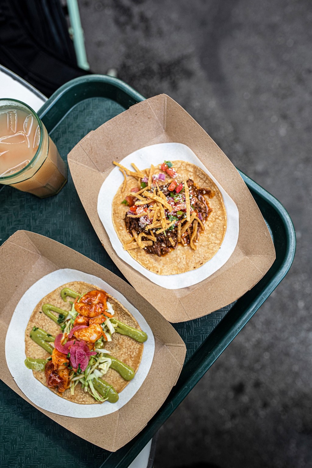 two tacos in a box on a table with a cup of coffee