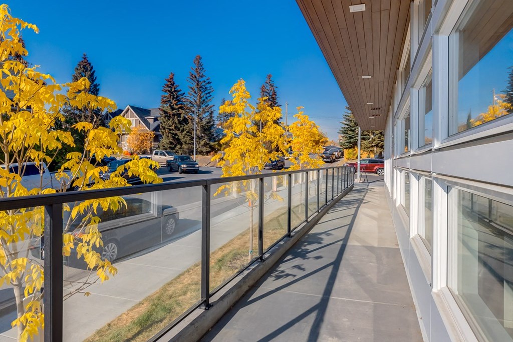A long balcony with yellow trees on the left and a building on the right.