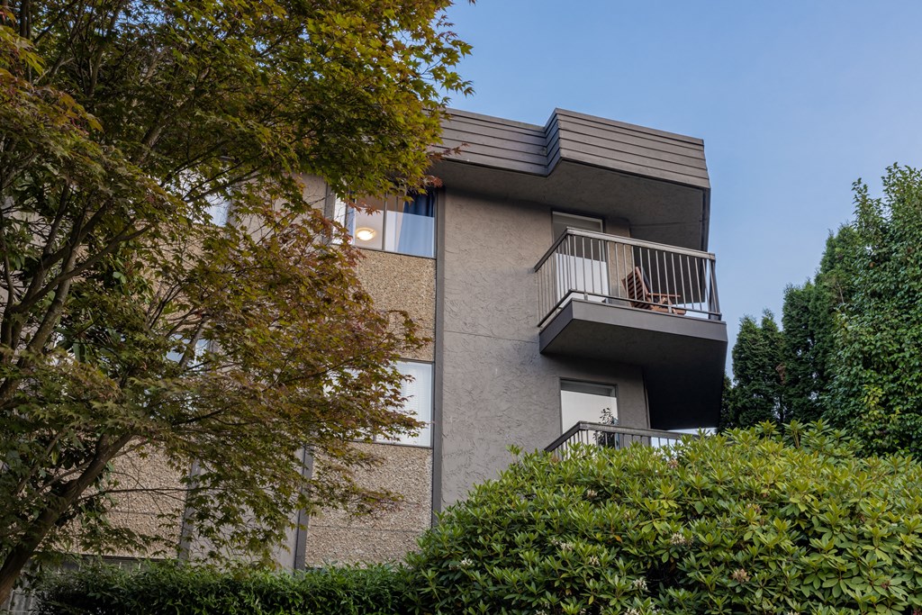 a woman sitting on a balcony in a grey apartment building