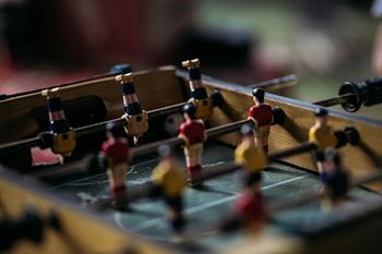 A foosball table with a red and yellow player on the left side.