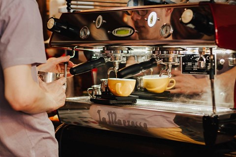 A person is making a cup of coffee at a coffee machine.