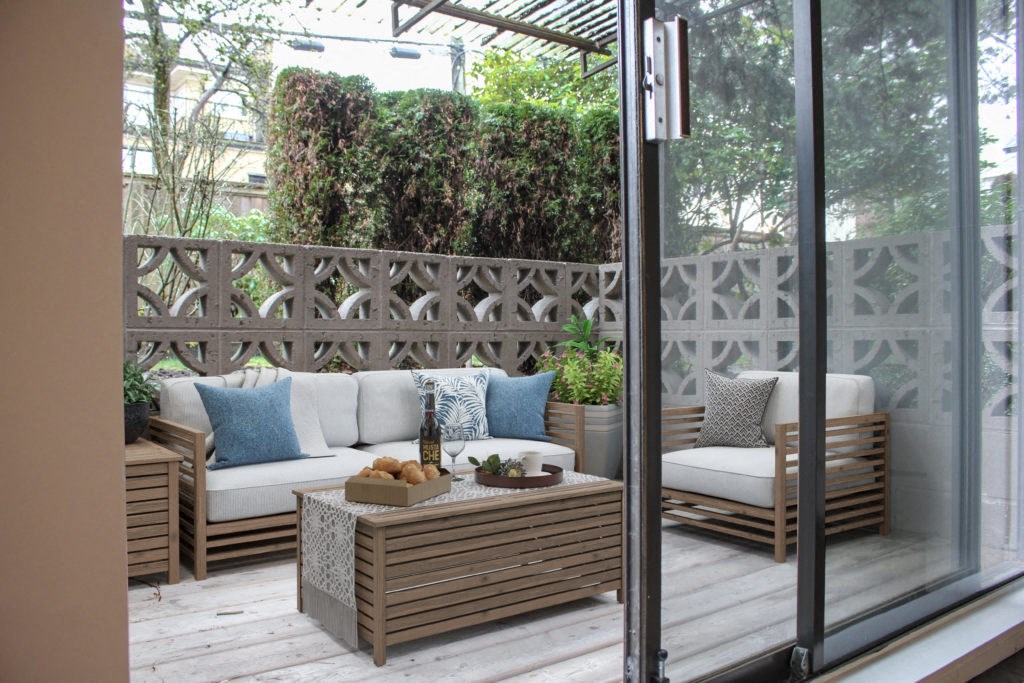 a patio with wooden furniture and a wooden fence in the background