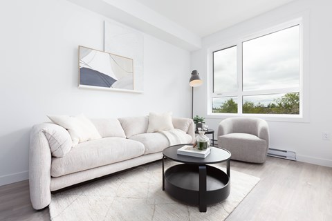 A modern living room with a white sofa, a coffee table, and a painting on the wall.