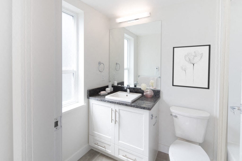 a bathroom with a white toilet and a white sink with a black countertop
