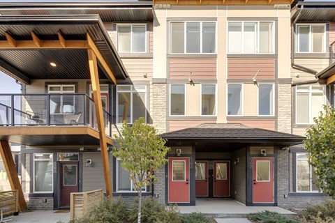 A modern house with a balcony and a red door.