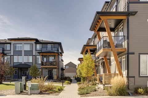 A modern two-story building with a balcony and a tree in front.