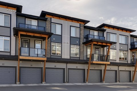 A row of modern townhouses with balconies and garages.