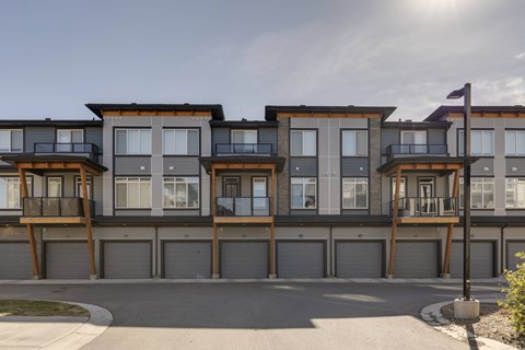 A row of modern townhouses with garages in front.