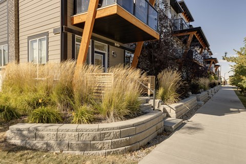 A modern house with a wooden balcony and a concrete walkway.