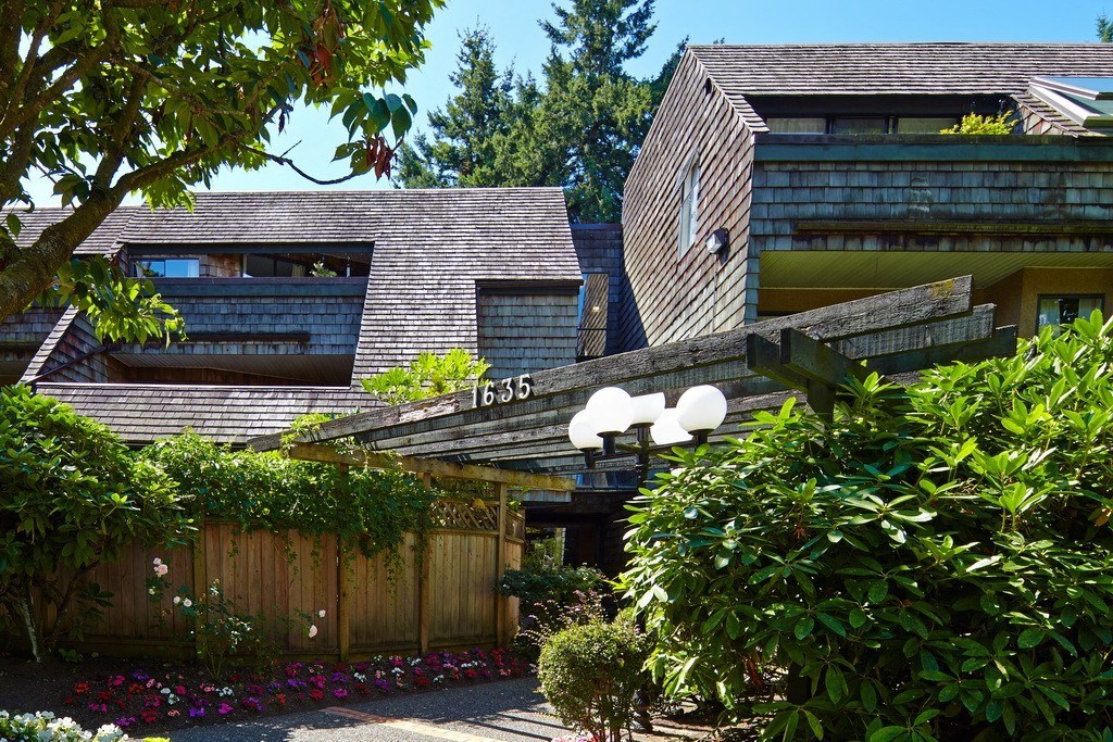 a house with a wooden fence and bushes in front of it