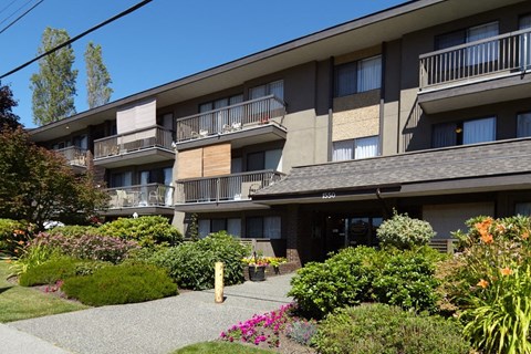 a large apartment building with balconies and a garden in front of it