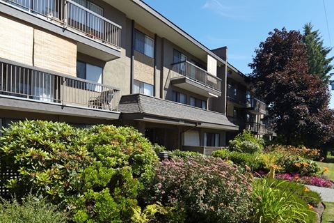 a large apartment building with balconies and a garden in front of it