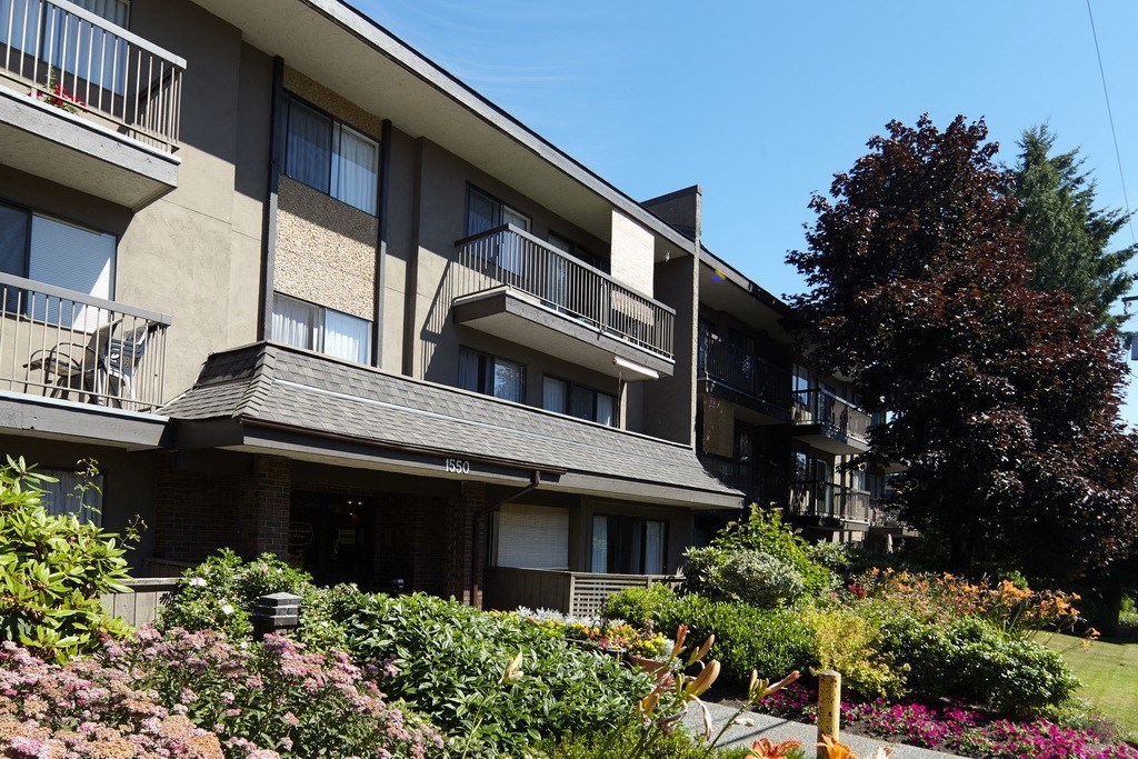 an apartment building with balconies and a tree in the background