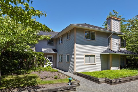 a house with a gray siding and a green lawn
