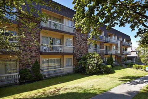 an apartment building with a grass yard in front of it