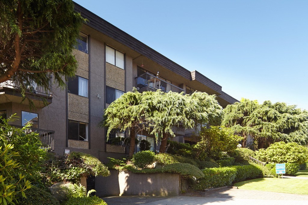 a large brick building with trees and bushes in front of it