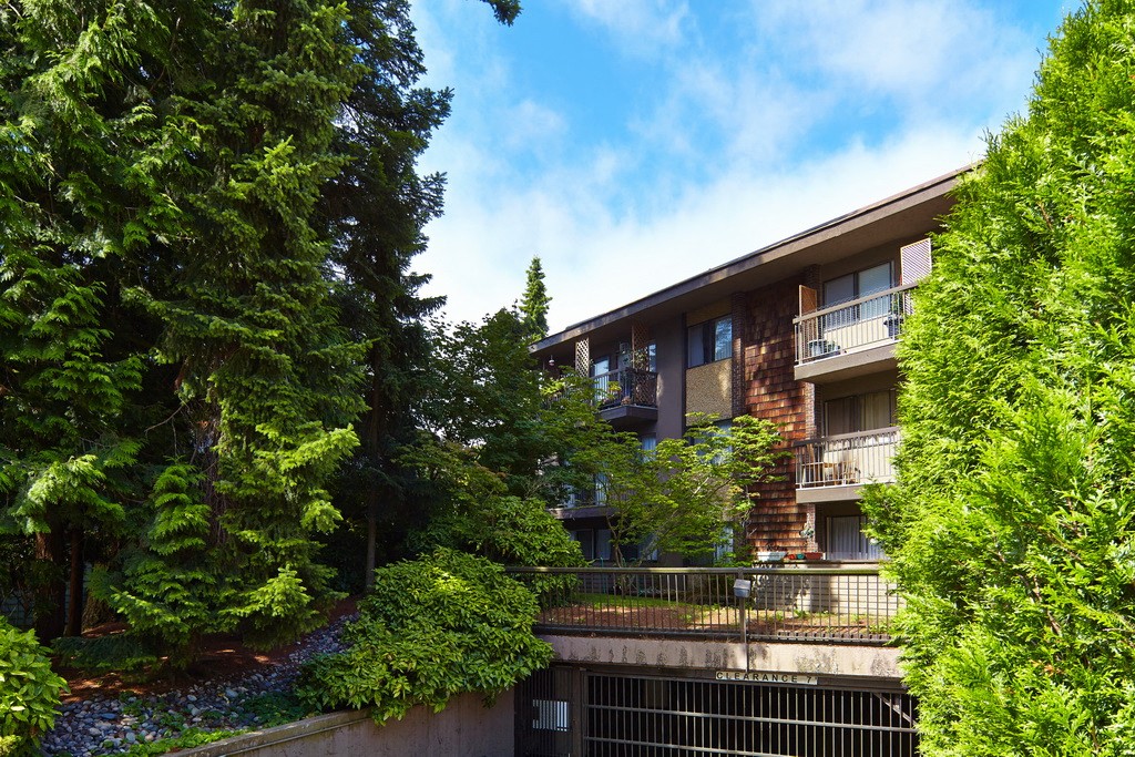 a picture of an apartment building with trees in the foreground and a blue sky in the background