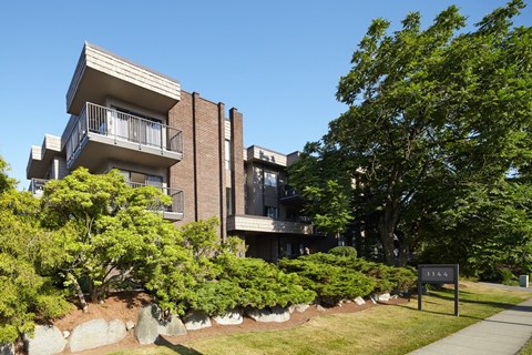 an apartment building on a sunny day with a sign in front of it