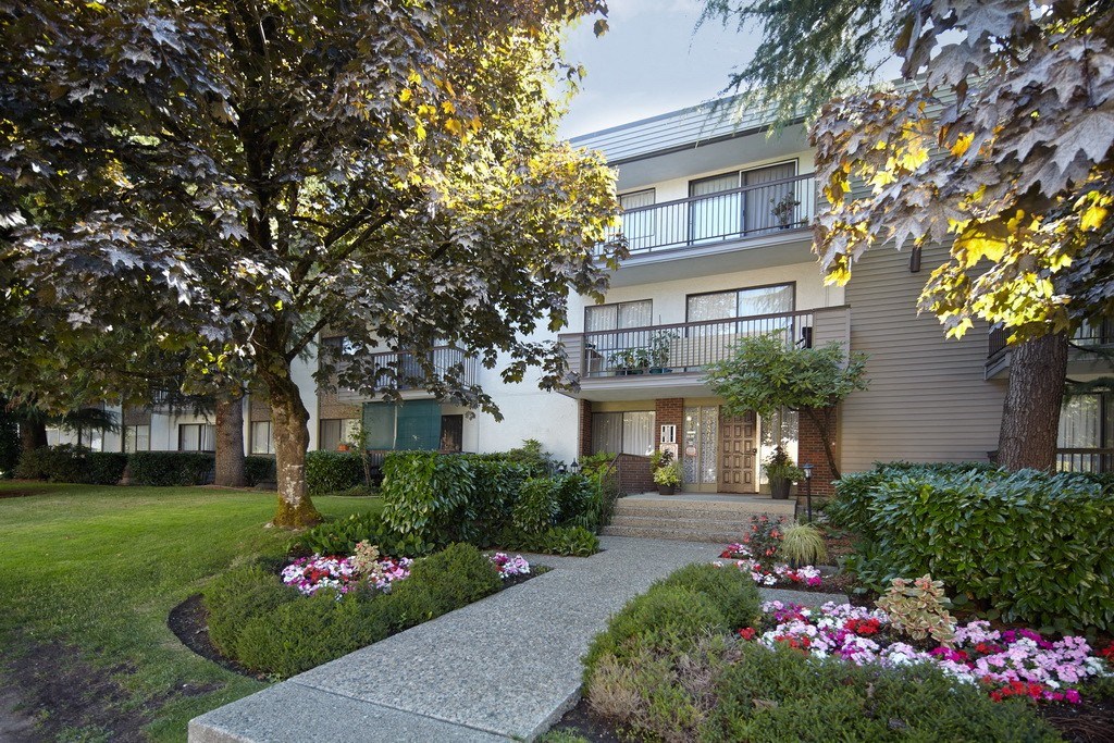 a picture of an apartment complex with a walkway in the middle of a grassy area